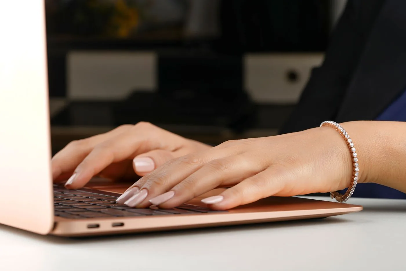 Hands wearing a bracelet working on a laptop
