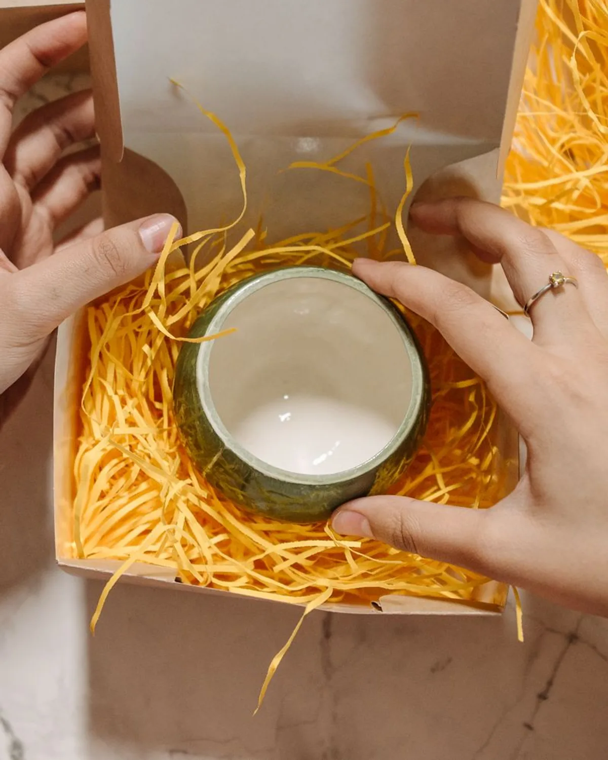 Hands placing a ceramic product into a shipping box